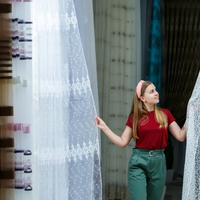 Mujer eligiendo cortinas a medida para una decoración luminosa en Marbella.